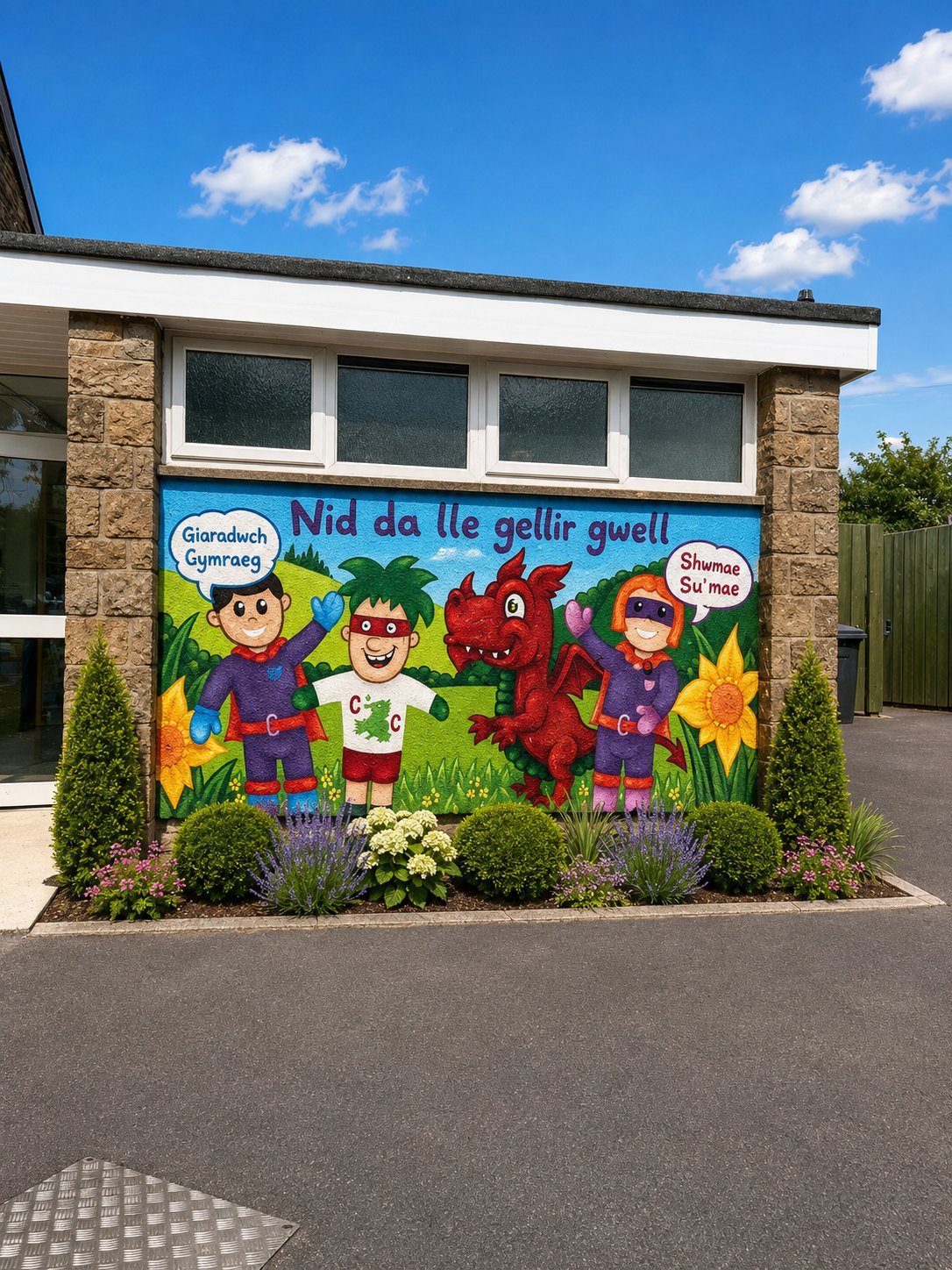 School entrance framed by brick columns, a flowerbed and a colourful Welsh-themed mural