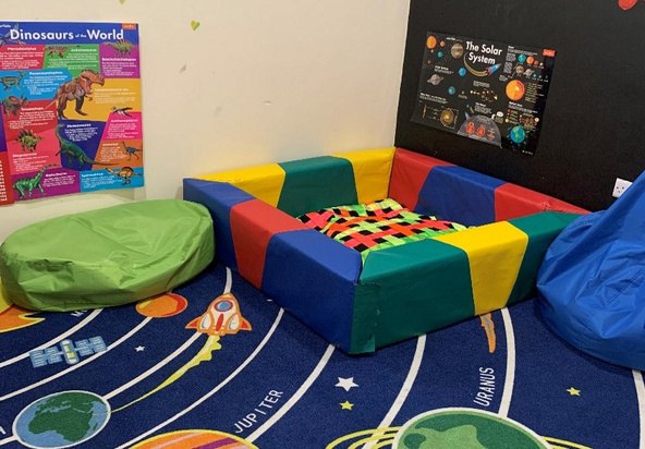 Sensory and reading corner with a soft play pit, bean bags and a solar-system floor rug